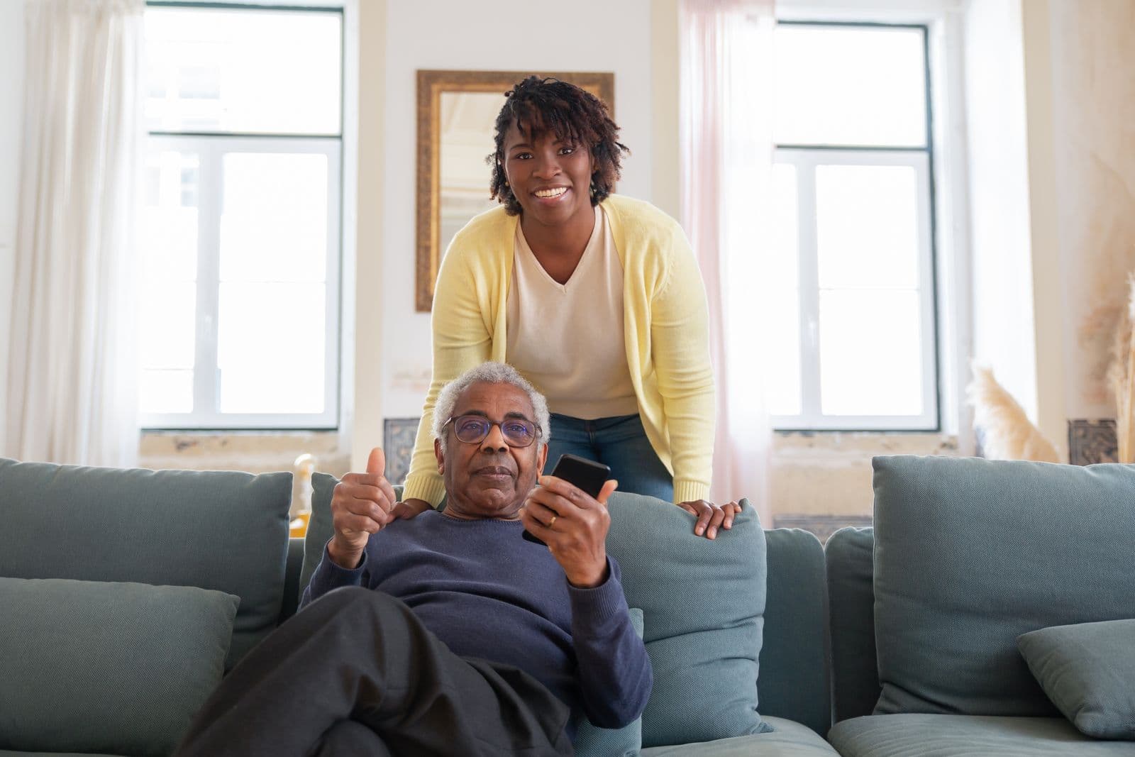 A care worker smiling with an older person in a bright home living room.