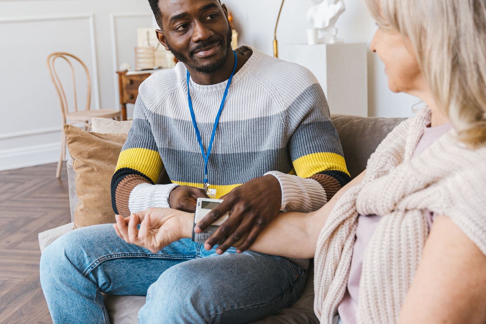 A care worker checking an older woman's blood pressure at home.