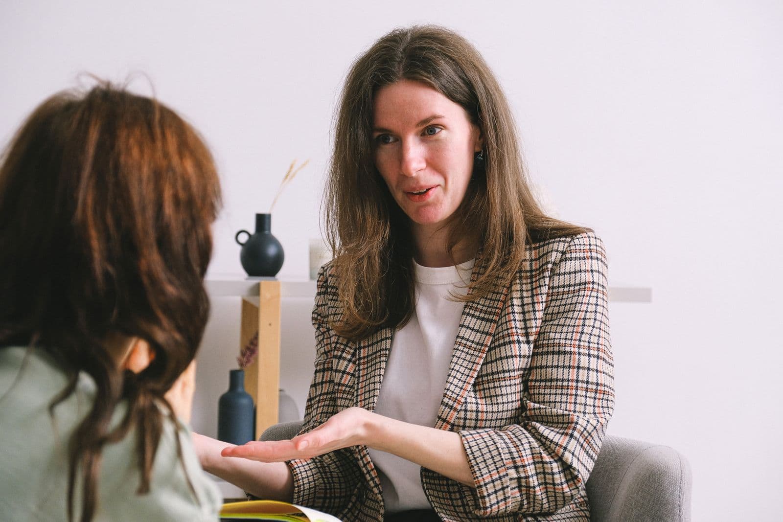A mental-health support worker talking with a client in a bright room.